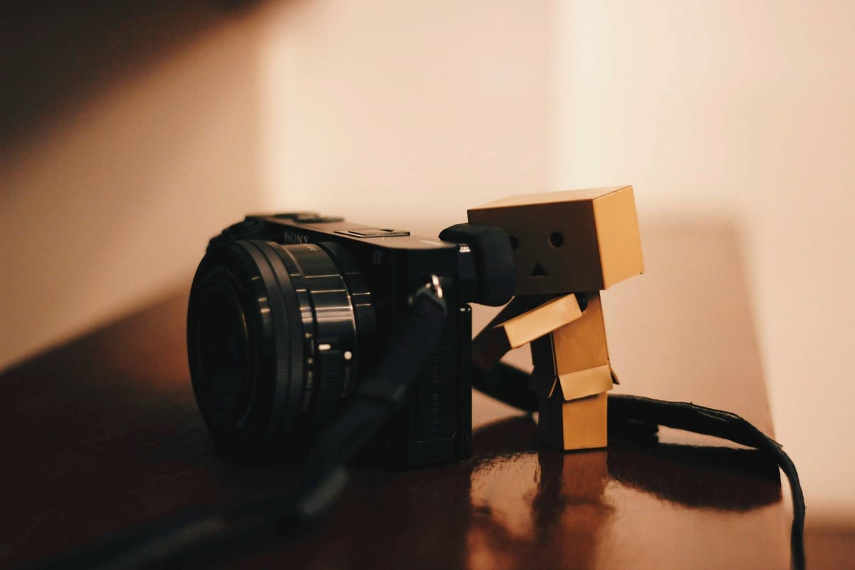 humanoid figure holding a black camera