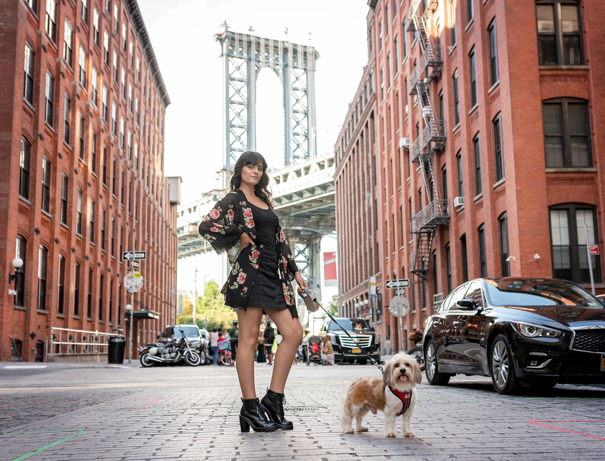 Woman standing in front of Brooklyn Bridge in New York with her dog