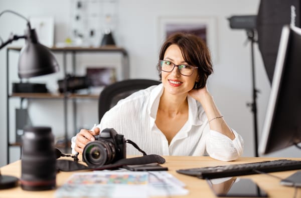 Professional photographer working on her computer with her camera gear on her desk